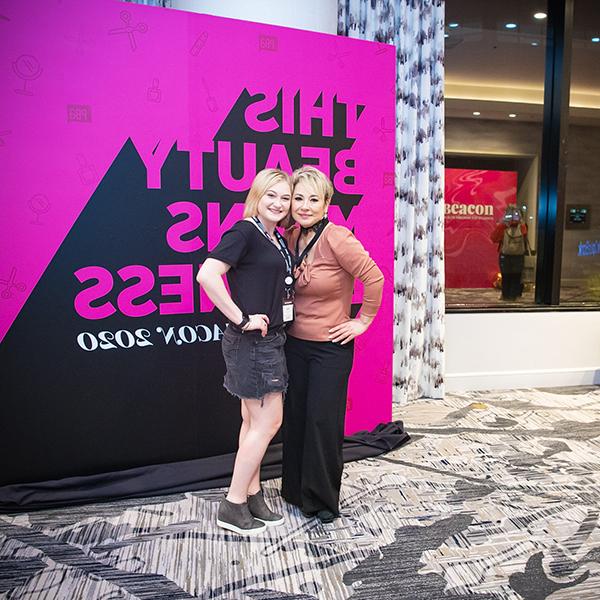 Mother daughter posing together in front of a large billboard